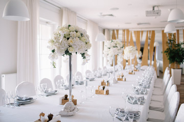 Tall vases with white flowers stand on a long dinner table