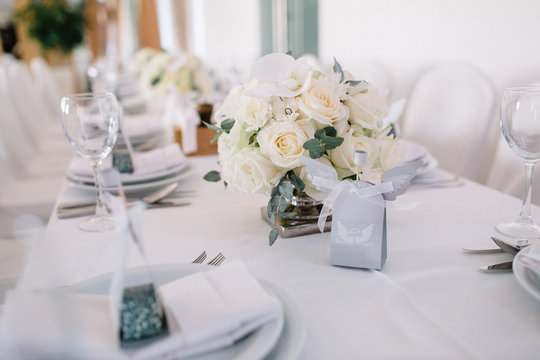 Bouquet of white roses stands on white dinner table