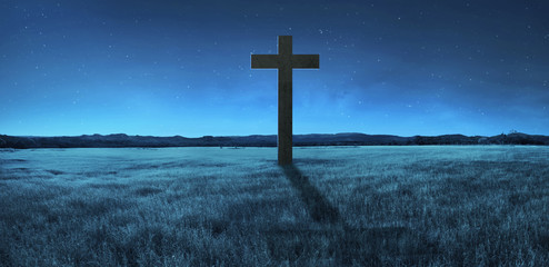 Christian cross in the middle of meadow