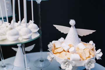 White bowl with cookies and marshmallows decorated with paper angels