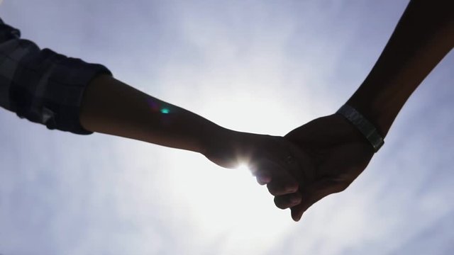 Low angle view of unrecognisable romantic couple strating to hold hands as they stand together and then separating them