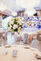 Tall vase with white and green flowers stands on round dinner table number nine