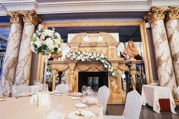 Large golden fireplace between marble columns decorated with white roses