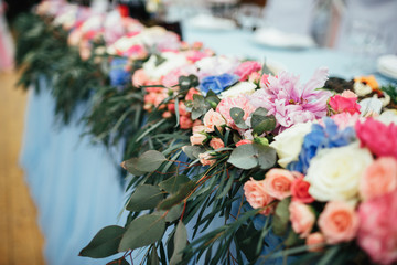 Dinner table for newlyweds decorated with blue cloth and pink flowers