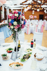Glass vase with silver candles, pink and blue roses stands on the dinner table number nine