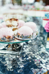 Dishes with pink and blue sweets stand on silver table