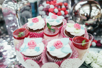 Dishes with pink and blue sweets stand on silver table