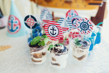 Fototapeta na wymiar Glasses with tiramissu and colorful berries decorated with anchors, yachts and other marine theme