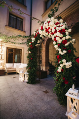 Fototapeta na wymiar Wedding altar made of red and white flowers and dark greenery