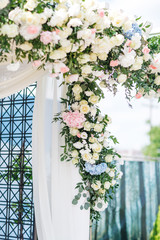 rich flower garland made of white roses and blue hydrangeas hangs on the white ladder