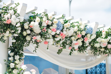 rich flower garland made of white roses and blue hydrangeas hangs on the white ladder