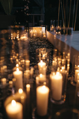 Shiny white candles stand on the ground in the darkness