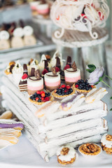Baked baskets with berries stand among other delicious desserts on the table