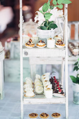 White ladder with flowers and cookies stands on the candy bar