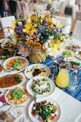 Colorful bouquet made of field flowers stands in the middle of dinner table
