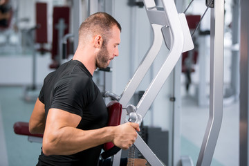 Fototapeta na wymiar muscular man working on fitness machine at the gym