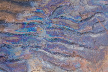 Colorful patterns of oil in the beach sand. Pollution patterns on the shore of Baltic sea. Colorful, abstract shapes on an ecological matter.