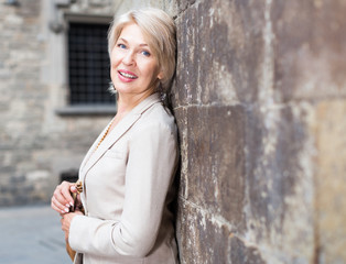 Elegant mature woman is posing near old wall