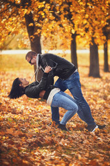 Young couple fooling in a park at autumn