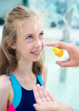 Woman applying sunblock cream on daughter's face.