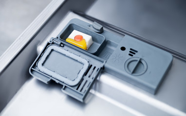 Detergent tablet in dishwasher machine close up