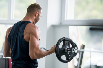 Naklejka na ściany i meble Man lifting weights, training, gym