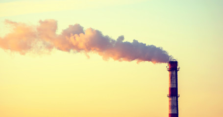 Photo of factory pipe with smoke at sunset