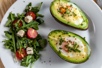 Zapiekane awokado z jajkiem posypane natką pietruszki i sałatka z rukoli, pomidorków koktajlowych i sera feta © Kamila Sankiewicz