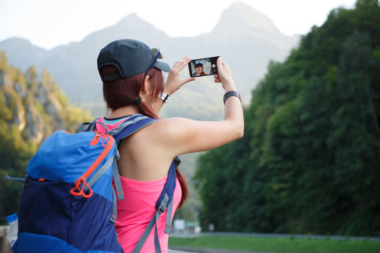 Image from back of tourist woman photographing mountain