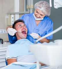 Dentist performing treatment to young man