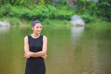 Fototapeta premium Beautiful asian girl in black dress smiling near by the river