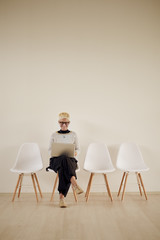 Businesswoman using laptop while sitting on chair in waiting room