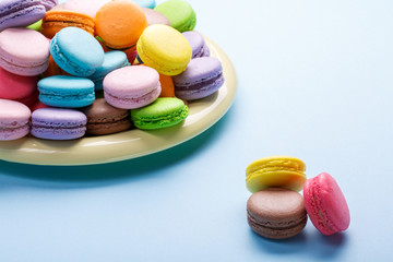 Assortment of macaroons cookies on black plate over blue background