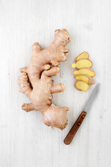 Big ginger root and knife on the white wooden table
