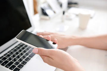 Hands of a woman who verifies the information of the phone and computer