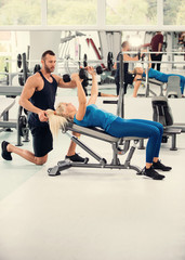 Fototapeta na wymiar Young couple working out with dumbbells at gym