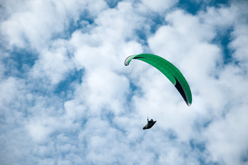 Paraglider flying in the blue sky against the background of clouds. Paragliding in the sky on a sunny day.