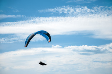 Paraglider flying in the blue sky against the background of clouds. Paragliding in the sky on a...