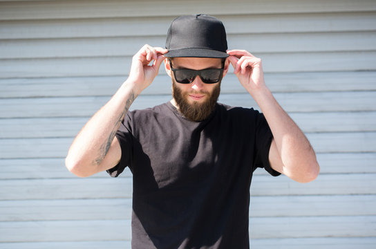 Hipster man wearing black T-shirt and a black hat with space for logo