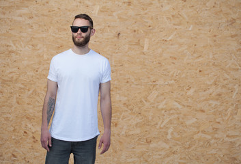 Hipster handsome male model with beard wearing white blank t-shirt with space for your logo