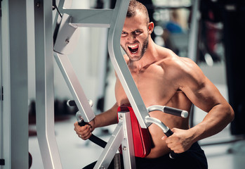 muscular man working on fitness machine at the gym