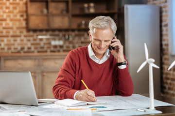 Senior engineer talking on the phone and making notes