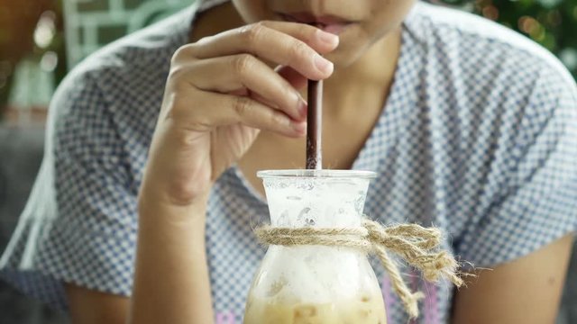 Close up Asian woman drinks ice coffee in coffee shop.

