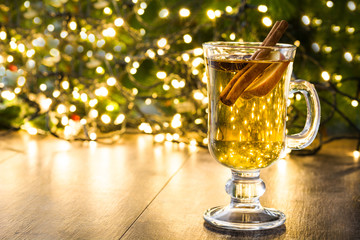 mulled cider in glass, ornaments and christmas light on wooden table.Copyspace
