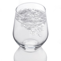 Transparent Glass of sparkling water in movement isolated on white background. Water splashing