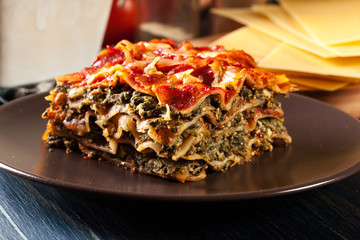 Piece of tasty hot lasagna with spinach on a plate