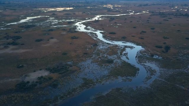 Shallow floodplain at sunset crossed by animal tracks on the Okavango delta aerial shot