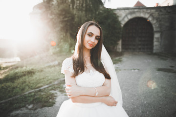 Happy beautiful young bride outside on a summer meadow at the sunset