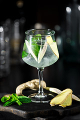 Ginger cocktail on dark background with mint and ice
