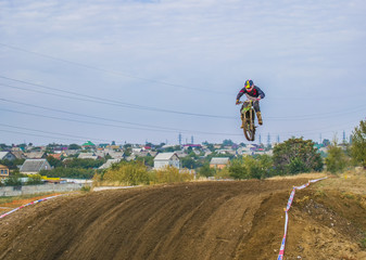 The racer on a motorcycle participates in a motocross race, takes off and jumps on a hill.